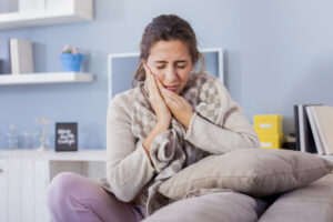 woman suffering from toothache while sitting on her bed