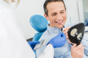 A man with a smile sits in a dentist chair, undergoing a dental implant procedure.